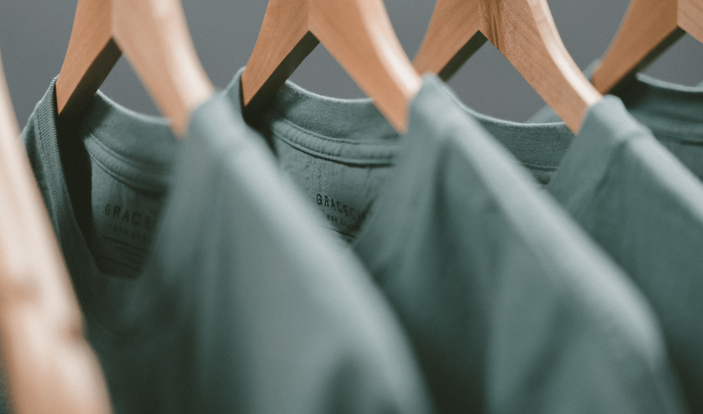 A row of green t-shirts on coat hangers.