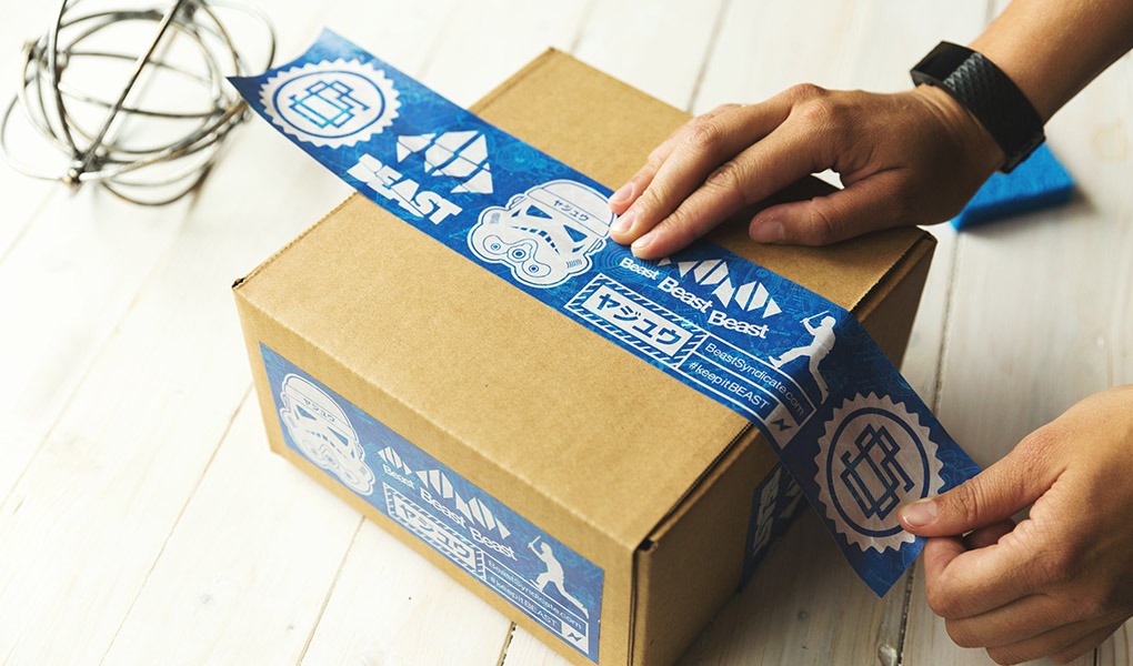 A person applies parcel tape to a cardboard box.